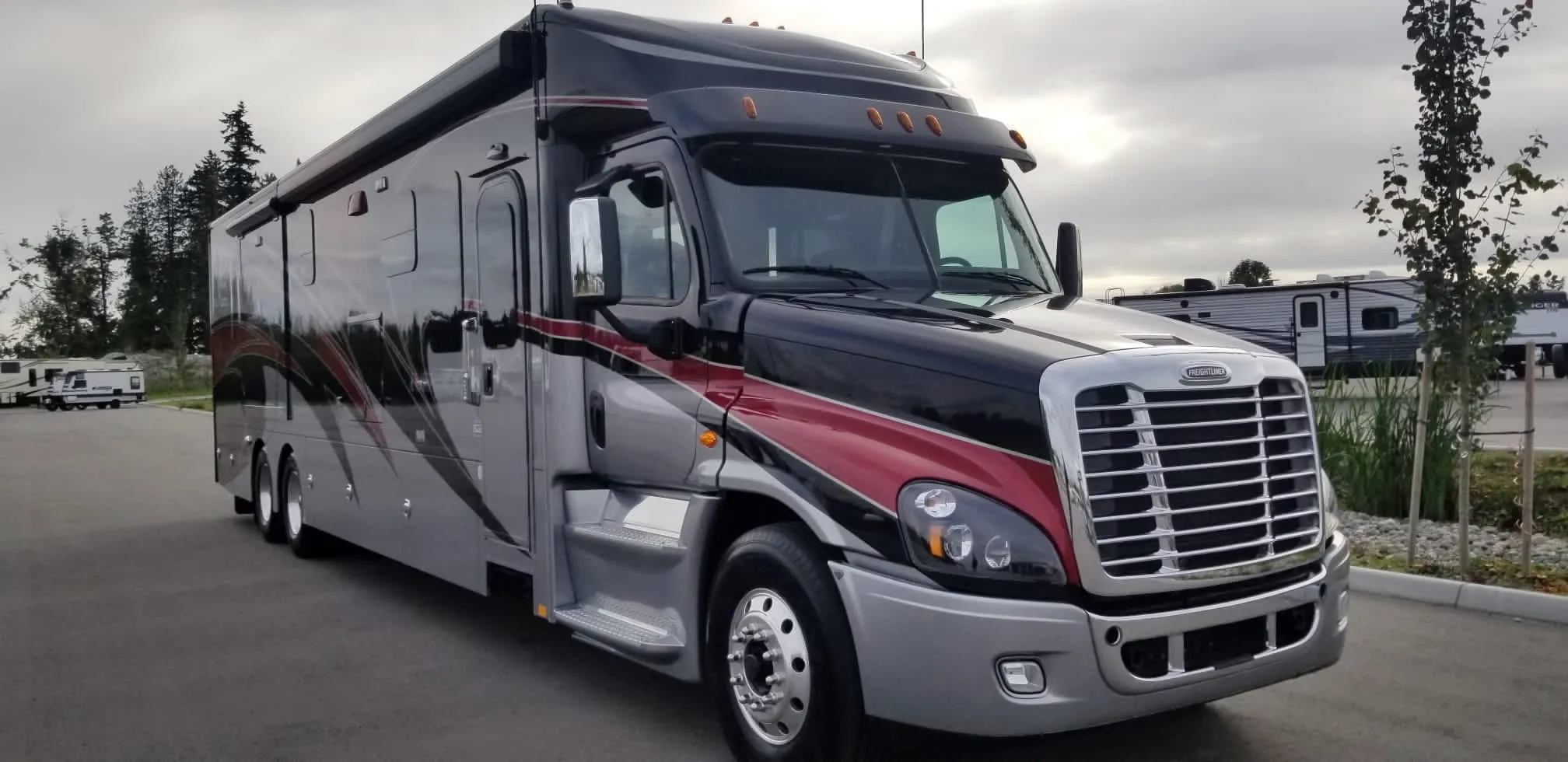 A Freightliner-chassis motorhome parked at an RV lot, ready for a drive-away